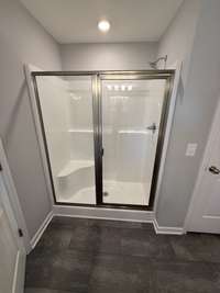 primary shower with a seat & shower door