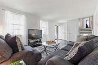 Another view of the living room, showing the front entrance, coat closet, and stairs to the 3rd level.