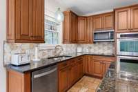 Enjoy views of the backyard oasis from this spacious kitchen, complete with a granite island, an abundance of cabinetry, upgraded backsplash, and a cozy eat-in breakfast area. Just steps away from the outdoors—perfect for everyday living!