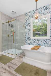 Spacious main-floor primary bedroom with a professionally updated, spa-like bathroom featuring a soaking tub, walk-in shower, double vanities, and large walk-in closets—your personal retreat awaits!