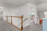 The upstairs hallway overlooks the entry and living room below, creating an open, airy feel. It leads to three additional bedrooms and a spacious bonus room—perfect for extra living space, a playroom, or home office.
