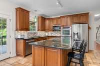 Enjoy views of the backyard oasis from this spacious kitchen, complete with a granite island, an abundance of cabinetry, upgraded backsplash, and a cozy eat-in breakfast area. Just steps away from the outdoors—perfect for everyday living!