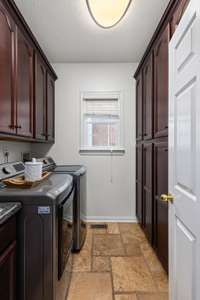 Laundry room featuring durable tile floors, an updated backsplash, and plenty of beautiful cabinetry—offering both style and ample storage for all your laundry needs!