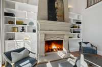 Cozy up by the fireplace in this inviting great room, now featuring custom bookshelves and upgraded lighting for a refined touch.