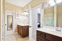 First full upstairs bathroom with separate vanities, linen closet, and door into the attic