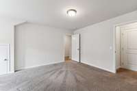 This view captures the top of the stairs across the room and entry doorway.  Door to the right is the closet and floored storage.