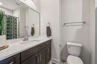 The bathroom features a large vanity with quartz countertops, decorative tile flooring, and a tile-surround shower/tub combo, combining both style and practicality.
