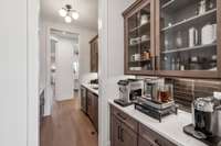 Designed for effortless entertaining, the Butler’s wet bar serves as the perfect space for catering and social gatherings. A second bar area features a sink and wine refrigerator, ensuring convenience for hosting.