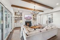 A gas fireplace, iron chandelier, and sconce lighting infuse the space with warmth and charm, while a wall of windows and sliding glass doors invite natural light and stunning outdoor views.