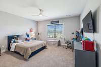 Bedroom Five offers plush carpeting, a double window overlooking the backyard, a ceiling fan, and a spacious walk-in closet.