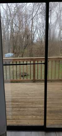 walk out to patio from the living room to a large deck over looking a fenced in yard.