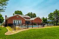 A view of the back of the home. The pool is enclosed with a black aluminum fence.
