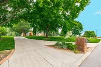 Split driveway entrance with brick mailbox & lush gardening.