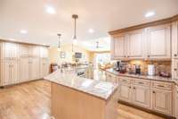 A wall of extra matching cabinets to the left, recessed lightning on ceiling & under the counter lighting.