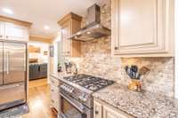 Travertine backsplash and additional countertop encompass the gas range.