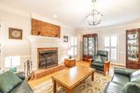 The spacious living room has a gas fireplace with an attractive mantle,  crown moldings, hardwood floors, recessed lighting and chandelier.