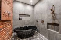 In the bath, an air jet tub with a ceiling fill and rain shower head is beautifully lined with original brick and encased in glass. This serene retreat defines luxurious comfort.