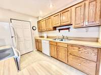 Open kitchen with oak cabinets, vinyl flooring, ample counter space, and seamless flow into the den overlooking a private, fenced courtyard.