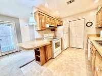 Galley kitchen with pantry, bar seating, washer/dryer hookups, and updated appliances including stove, refrigerator, hood vent, and dishwasher—perfect for convenient everyday living.