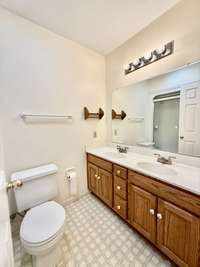 Guest bath with oak cabinet vanity with double cultured marble sinks;  vinyl flooring and tub/shower combo;