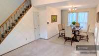 Combination Living Room and Dining Area with carpet floor coverings. Extra closet storage under the staircase leading to the Loft area