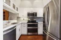Chic and functional kitchen with stainless steel appliances, glossy subway tile backsplash, and crisp white cabinets and counters with a modern feel.