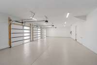 Oversized three car garage featuring three 10' x 10' doors and epoxy floor with EV charger plug in place. This space will easily accommodate three LARGE SUVs.