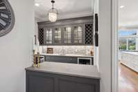 Wet bar, wine refrigerator with built-in cabinets and large additional storage pantry closet.