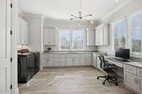 Abundant cabinet storage and office space with a utility sink in the laundry room.