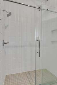 Guest Bathroom features Chic Tiled Shower with Transparent Glass Doors...