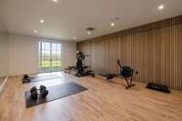 State-of-the-art gym with professional-grade hardwood sports flooring, a custom paneled wall, full mirror wall, and tall Marvin glass doors.