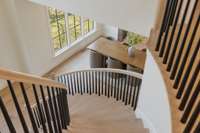A winding stair with custom balusters and railing guides one to the upper level, where there’s more than enough room for residents and guests alike.