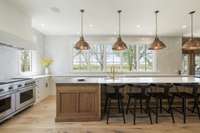 This chef's kitchen features a WOLF gas range with 6 burners and a griddle, a double oven, an additional wall oven, two dishwashers, and a paneled Sub-Zero refrigerator with several additional refrigerator and freezer drawers.