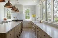 An oversized island with designer lighting, walnut-inlay cabinets, and fully custom built cabinetry offer beauty and function.