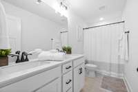 Primary bathroom with dual vanities, custom cabinets and marble counters
