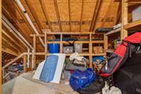 The attic landing off the upstairs bonus room features built-in storage shelves and easy walk-in access, offering a practical solution for seasonal items and organization.