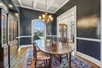 The formal dining room features a coffered ceiling, elegant trim, and rich wall tones. A beautiful space for hosting holidays and special occasions.