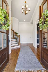 A grand entry welcomes you with soaring ceilings, warm hardwoods, and elegant trim details. The open staircase and natural light set a bright, inviting tone right from the front door.