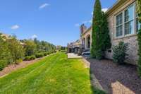 This spacious side yard is beautifully landscaped with privacy hedges and evergreens, offering both a scenic view and functional space for outdoor activities or future enhancements.