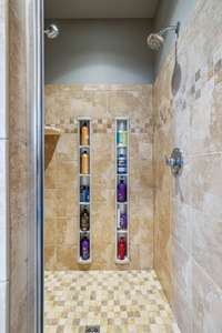 The walk-in shower features dual showerheads and built-in vertical shelving for effortless storage and convenience.