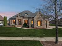 Evening curb appeal is enhanced by subtle soffit and landscape lighting, creating a warm and inviting glow that highlights the home's architectural charm.