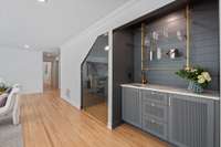 A Custom wine room located next to the wet bar featuring floating brass shelves and beautiful cabinetry.