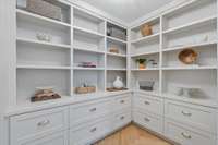 A large walk-in pantry with loads of storage and herringbone hardwoods