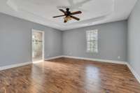 Modern spacious owners' suite with trey ceiling and a fan.