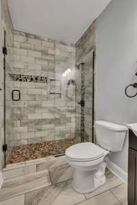 Bathroom #2 walk- in shower features beautiful tile with glass door and tiled flooring.
