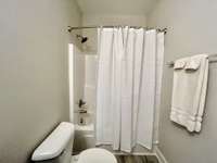 Guest bath has tub/shower combo with 6 ft vanity with marble top.