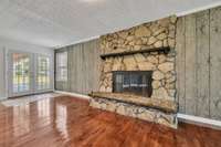 Another view of den featuring wood burning masonary fireplace.