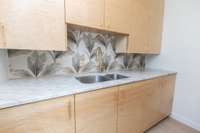 Laundroom sink with marble counters and loads of storage
