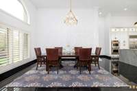 Host with style in this formal dining room featuring a striking full-height paneled accent wall. Ample natural light pours in through the oversized arched window, framing lush outdoor views.