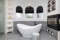 Take note of the corner floor-to-ceiling shelving and the clever spa-inspired towel storage above and below the see-through fireplace.